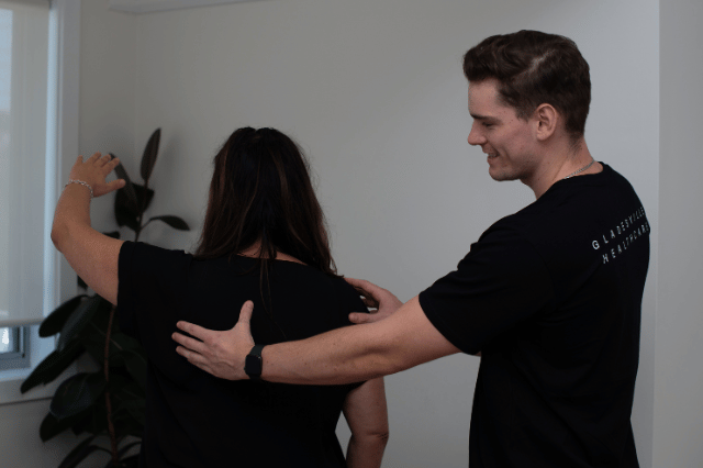 Male physiotherapist assessing female patient shoulder movement