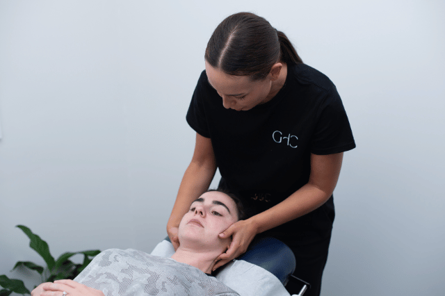 Female patient lying on treatment table and Gladesville Healthcare chiropractor treating neck pain and muscle tension