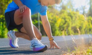 Person in athletic wear kneels, holding knee—occupational therapy for injury recovery needed.