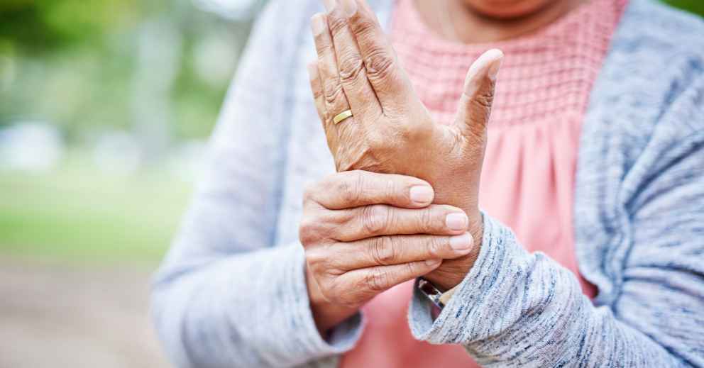 Person holding wrist, possibly in pain—OT support for arthritis in hands & wrists can help.